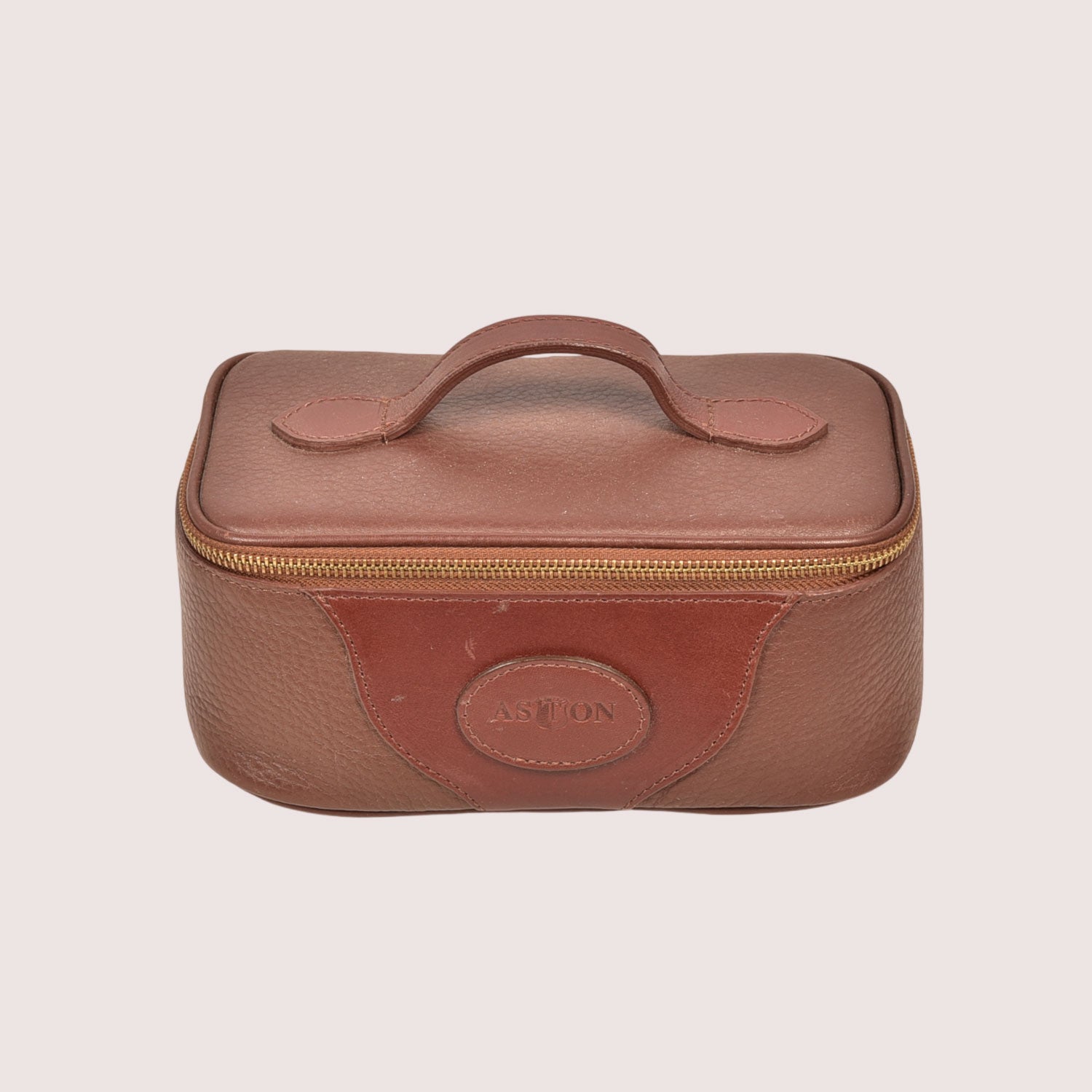Brown travel case with handle and visible brand logo on a beige background